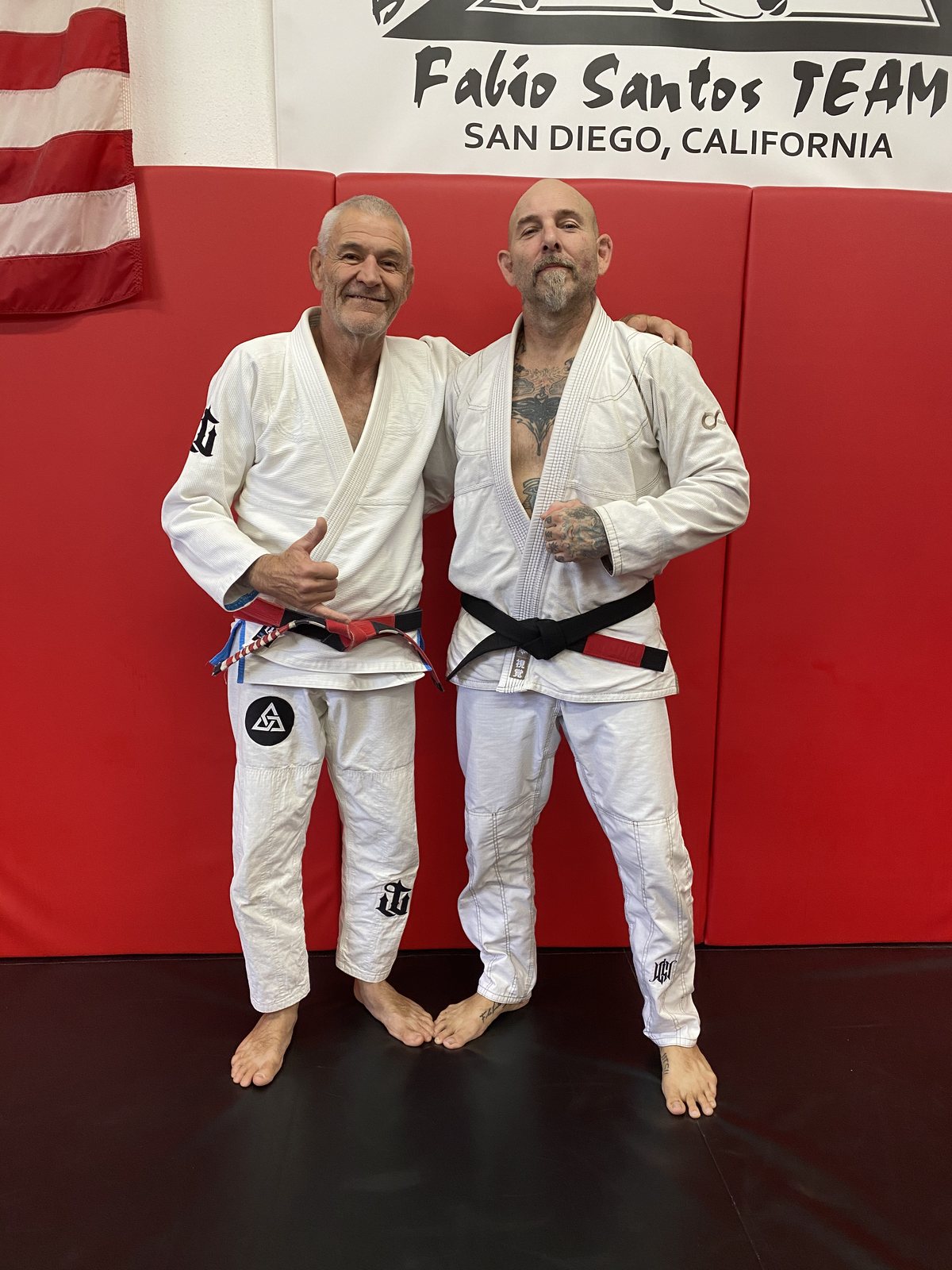 Coach Sean with a coral belt instructor beneath the Fabio Santos Team banner